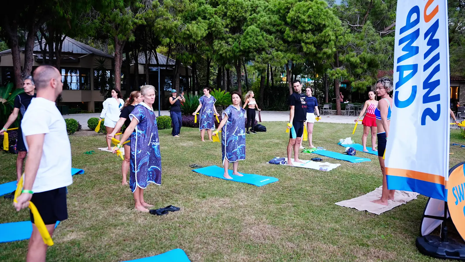 October 2026, Kemer: participants in Swim Up ponchos do dryland work with resistance bands on the lawn.