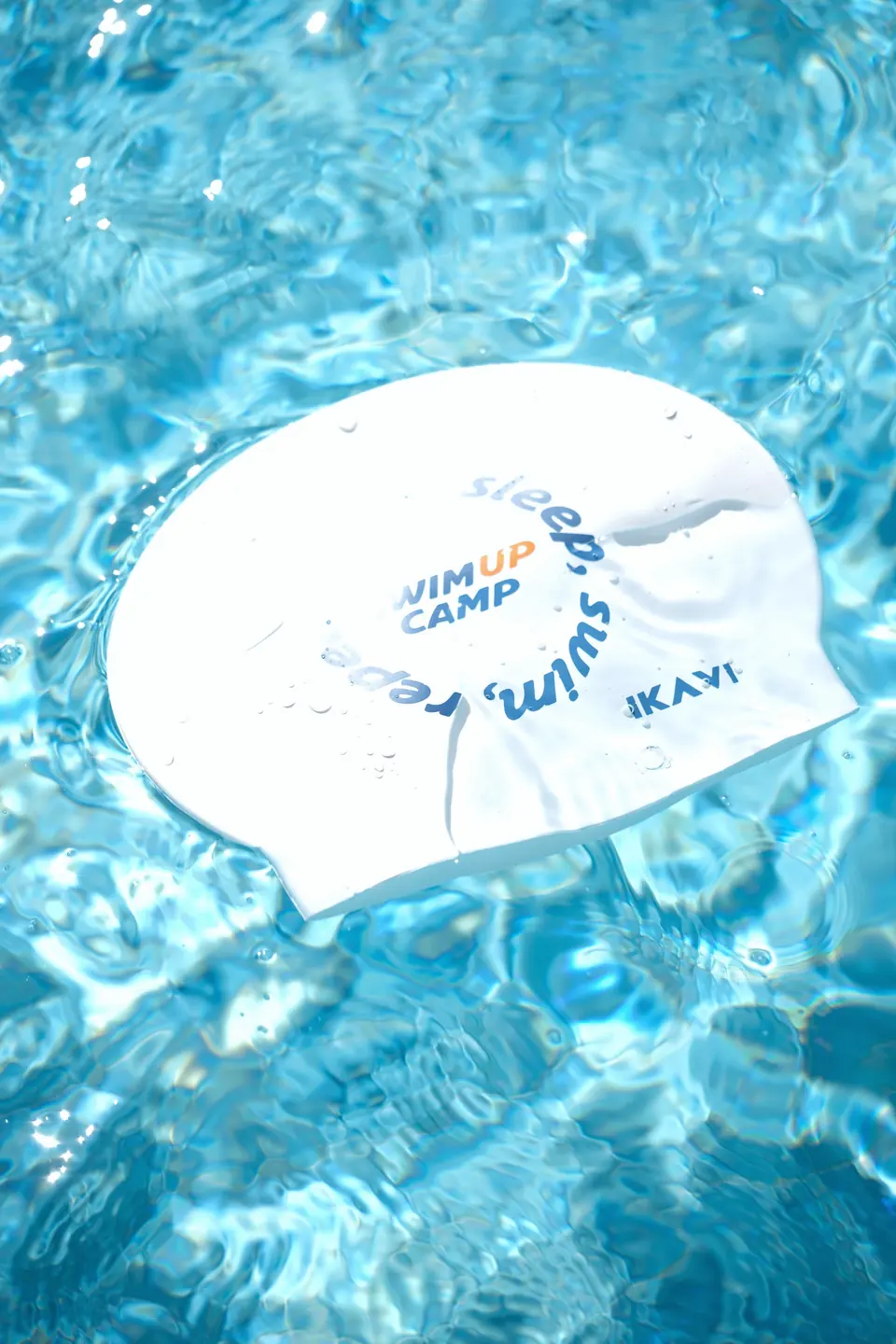 Havuz yüzeyinde duran beyaz Swim Up Camp bonesi, ışık yansımalarıyla.