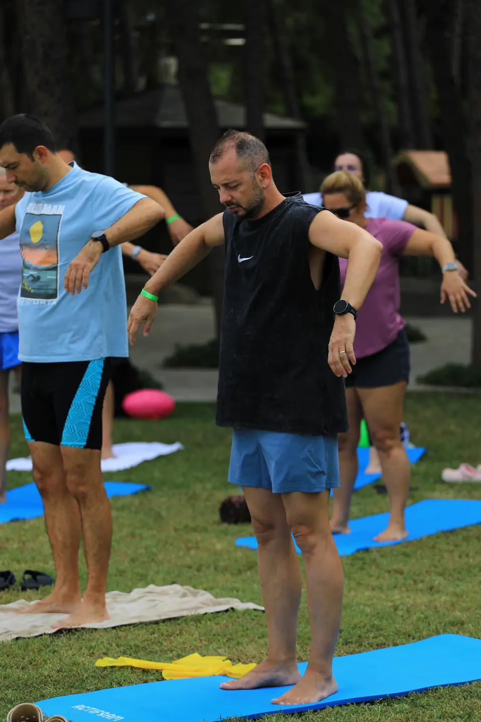 Çimde mat üzerinde kollar yana açık, gövde döndürme çalışması yapan grup.