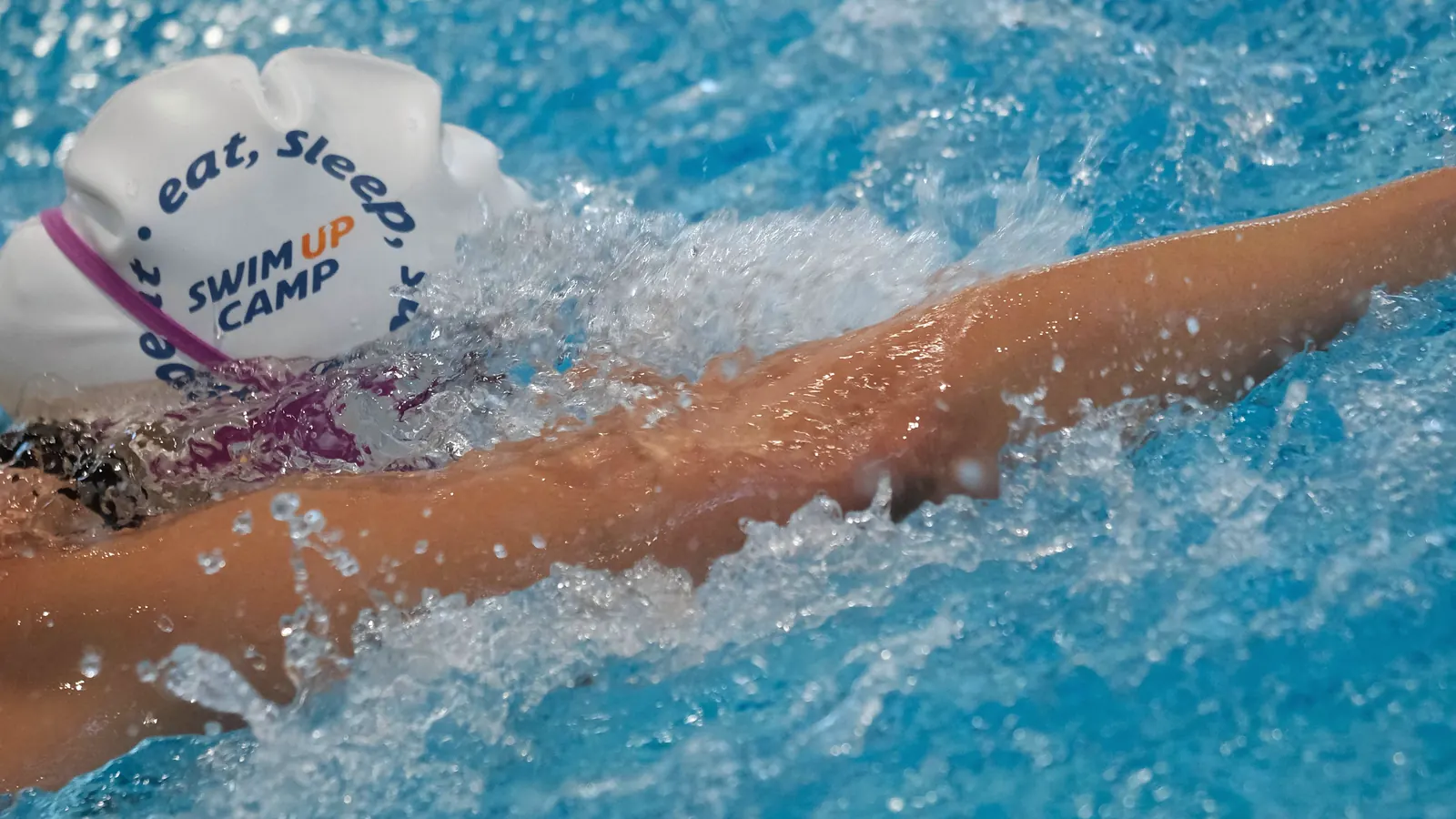 Şubat 2025, Gloria Sports Arena kapalı havuzu: Swim Up boneli bir yüzücü kolunu suyun üstünden ileri savuruyor.